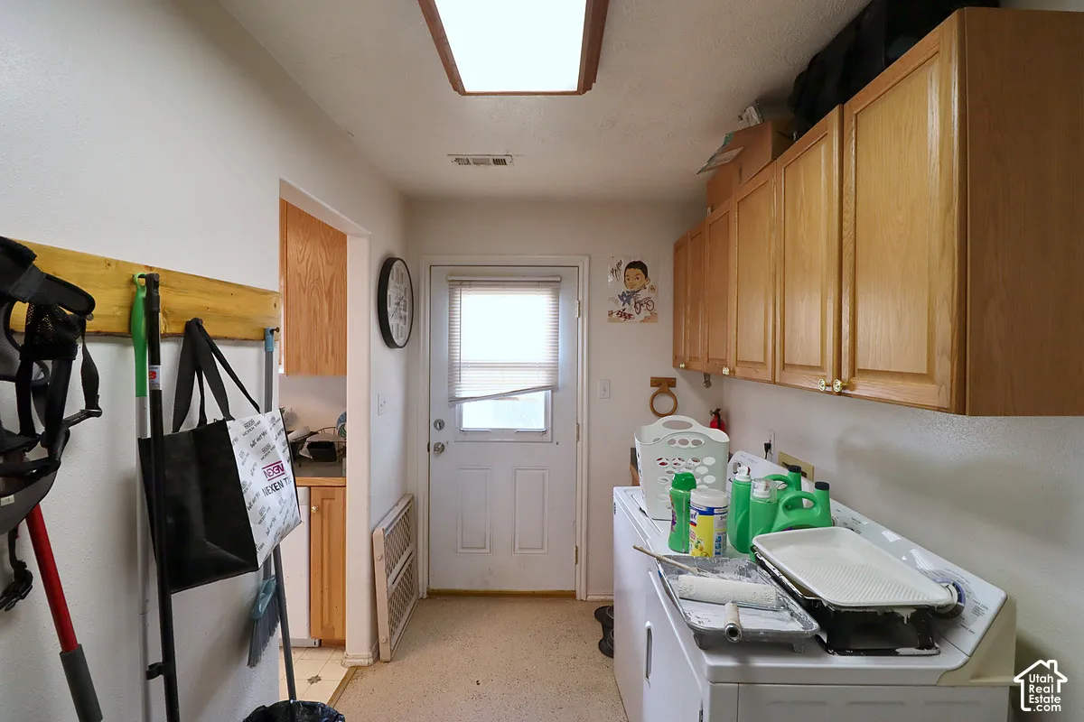 Utility room featuring extensive wall-mounted wood cabinetry, a flush-mount rectangular light fixture, and an exterior door with integrated window