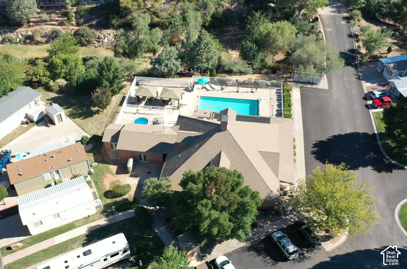 Aerial perspective of a property featuring an in-ground swimming pool, a separate in-ground spa, a hardscaped pool deck, and a multi-section roofline