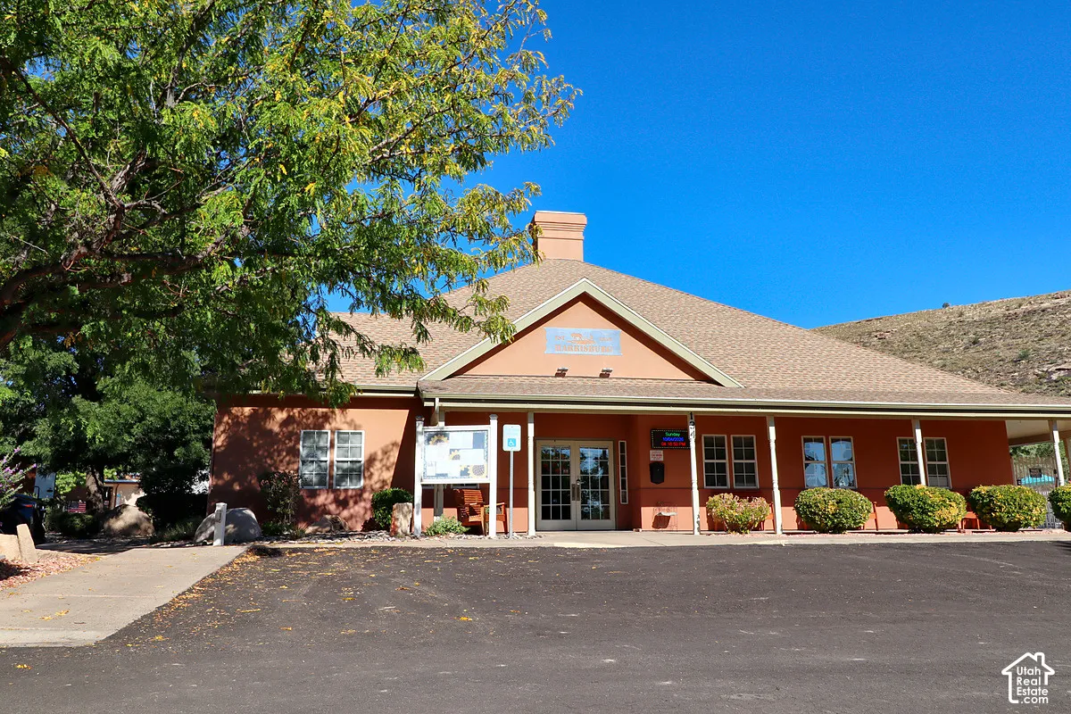 Stucco exterior featuring a pitched roof, covered front porch with support pillars, and double-entry glass doors