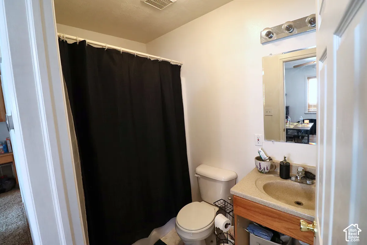 Bathroom featuring a wood-tone vanity with a solid surface integrated sink, wall-mounted mirror, multi-bulb vanity light fixture, and a shower-tub combination