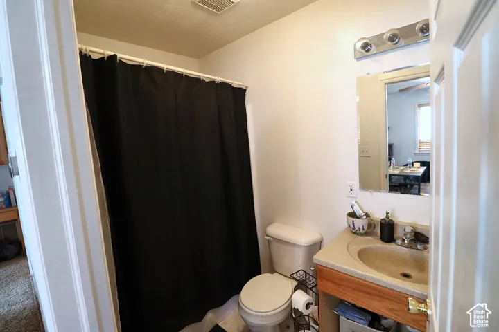 Bathroom featuring a wood-tone vanity with a solid surface integrated sink, wall-mounted mirror, multi-bulb vanity light fixture, and a shower-tub combination