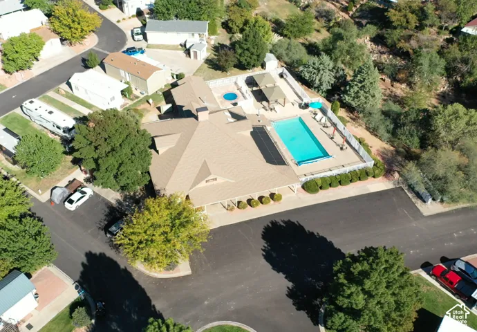 Aerial perspective featuring a shingled roof property with an in-ground swimming pool, a circular spa, covered patio space, and paved driveway