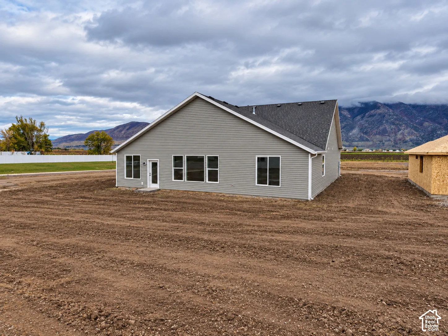 Grey lap siding exterior featuring a gable roof, white trim, multiple windows, and a full-height glass-paneled exterior door