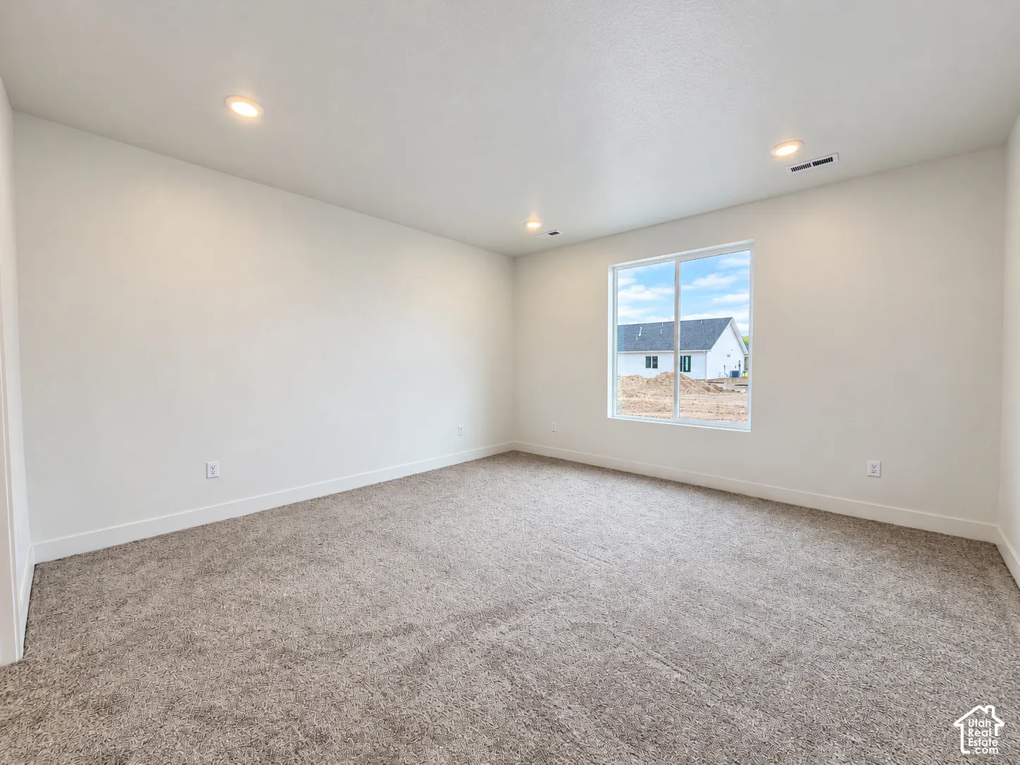 Neutral interior featuring wall-to-wall carpeting, recessed ceiling lighting, and a dual-pane sliding window
