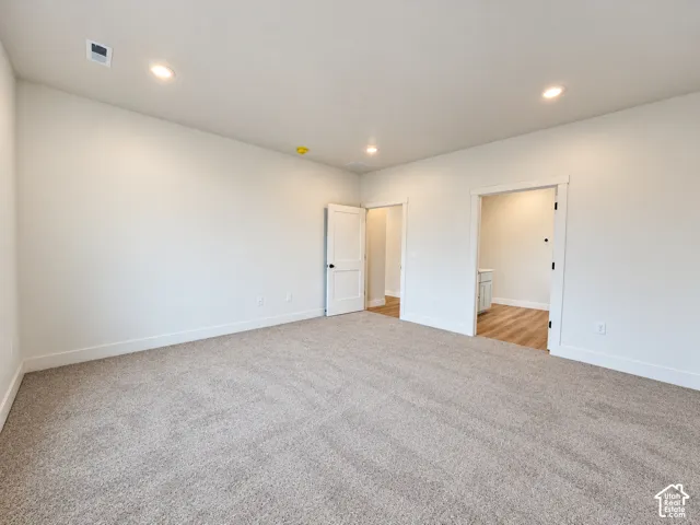 Neutral-toned carpeting, recessed ceiling lighting, and solid-core interior doors with matte black hardware