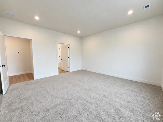 Neutral-toned carpeting, recessed ceiling lighting, and solid-core interior doors with matte black hardware