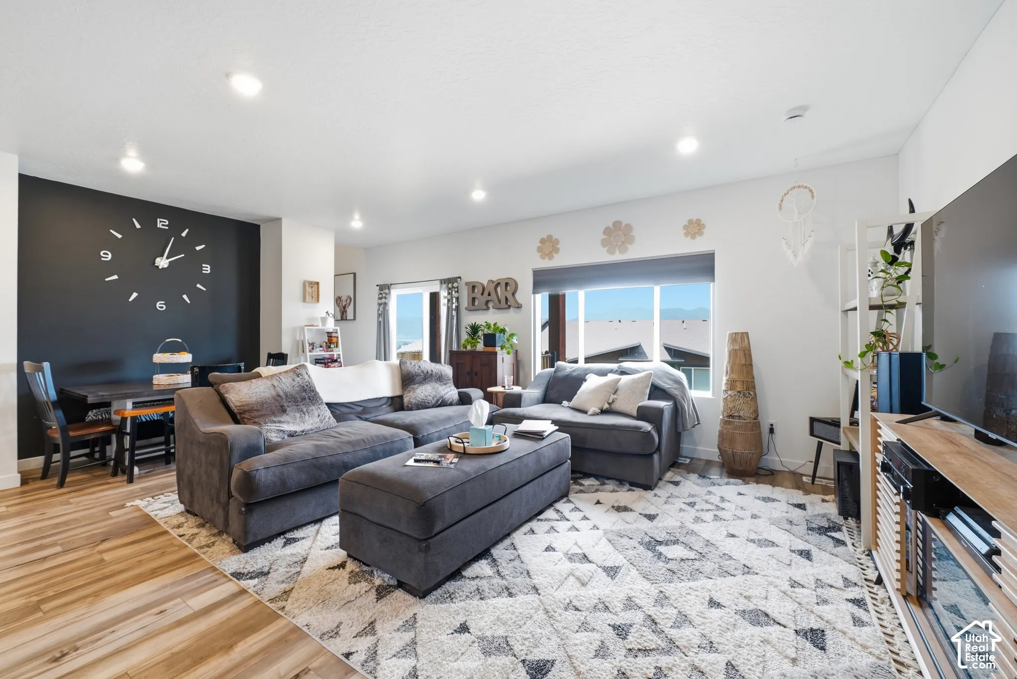 Living space featuring wood-finish flooring, a matte black accent wall, and recessed lighting