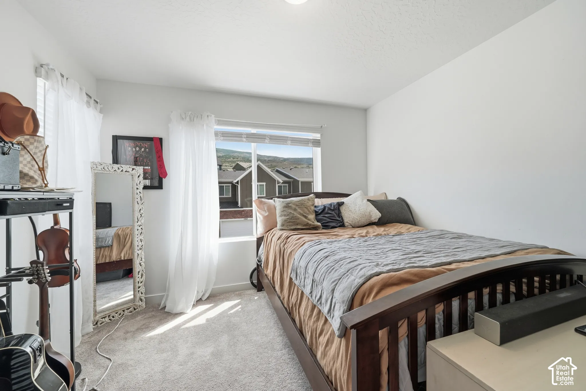 Neutral-toned interior featuring wall-to-wall carpeting, sliding window with mountain and residential exterior scenery, and white walls