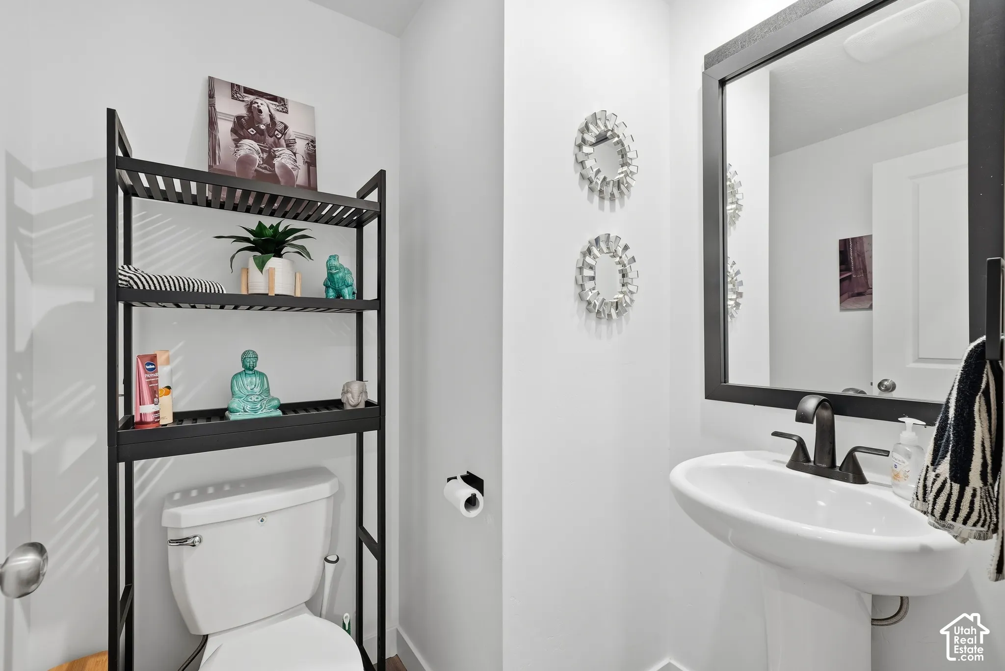 White pedestal sink, black-framed vanity mirror, and matte black plumbing fixtures