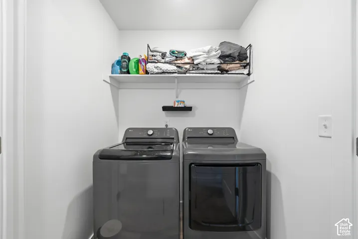 Laundry area featuring white walls, overhead wire shelving, and an additional wall-mounted shelf