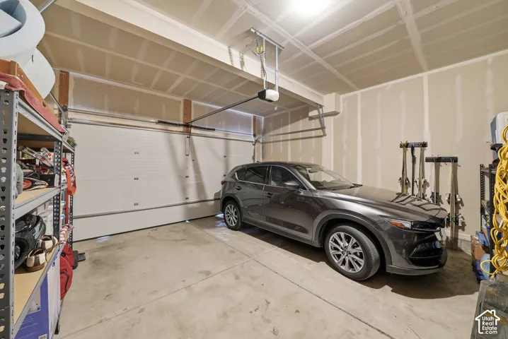 Attached garage featuring a concrete floor, motorized sectional garage door, and exposed structural ceiling beams
