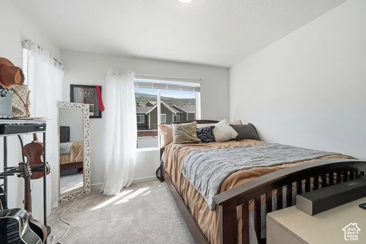 Neutral-toned interior featuring wall-to-wall carpeting, sliding window with mountain and residential exterior scenery, and white walls