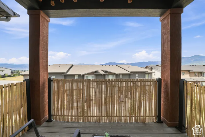 Covered outdoor balcony featuring wood-finish structural columns, natural reed screening, and mountain backdrops
