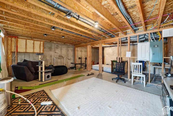 Unfinished basement level featuring exposed wood-joist ceiling, concrete foundation walls, stud-framed partitioning, and electrical service panel