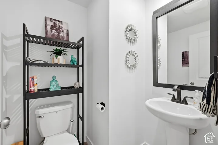White pedestal sink, black-framed vanity mirror, and matte black plumbing fixtures