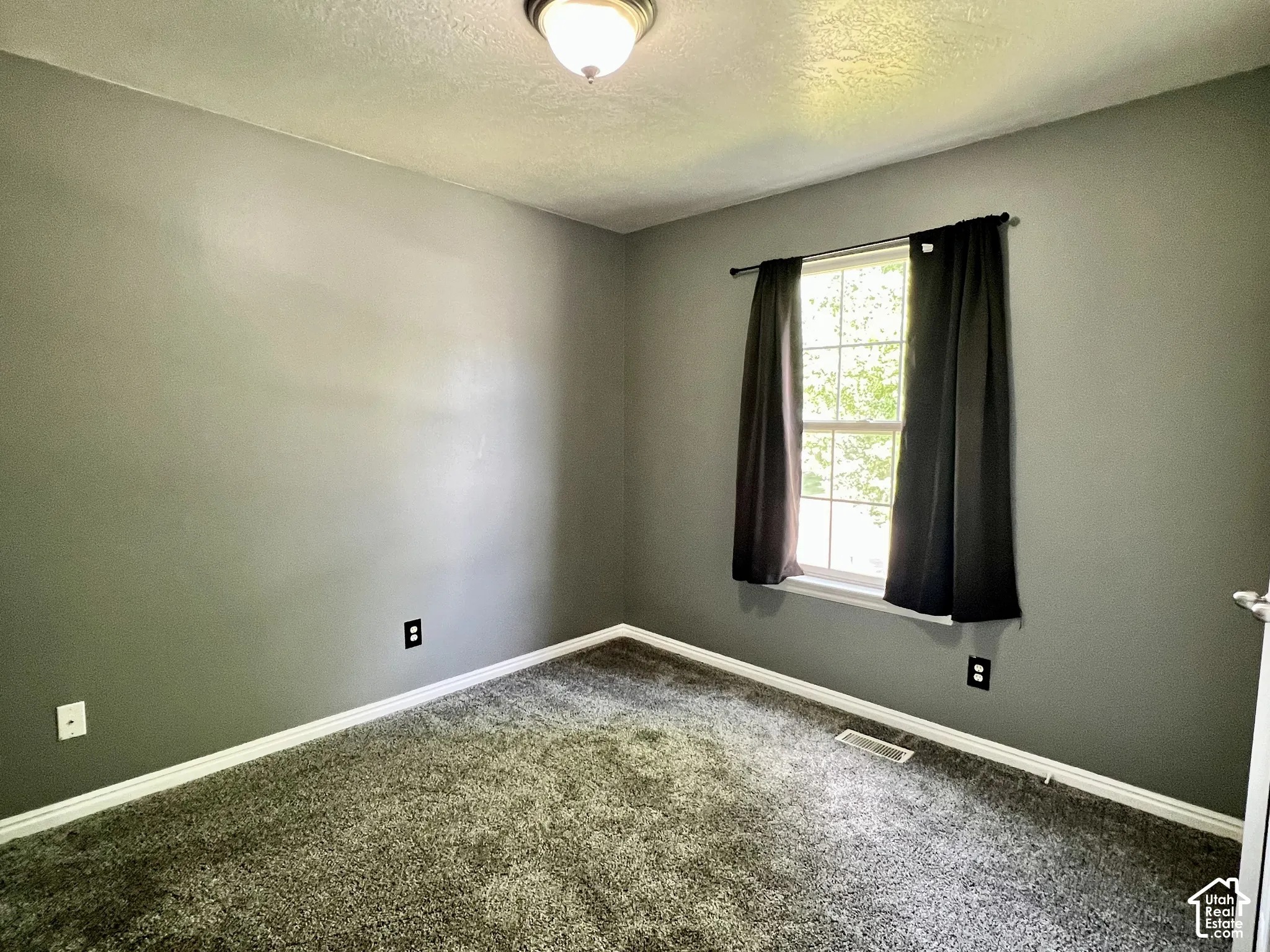 Neutral-toned interior walls featuring wall-to-wall carpeting, a grid-patterned window, and a flush-mount ceiling light fixture