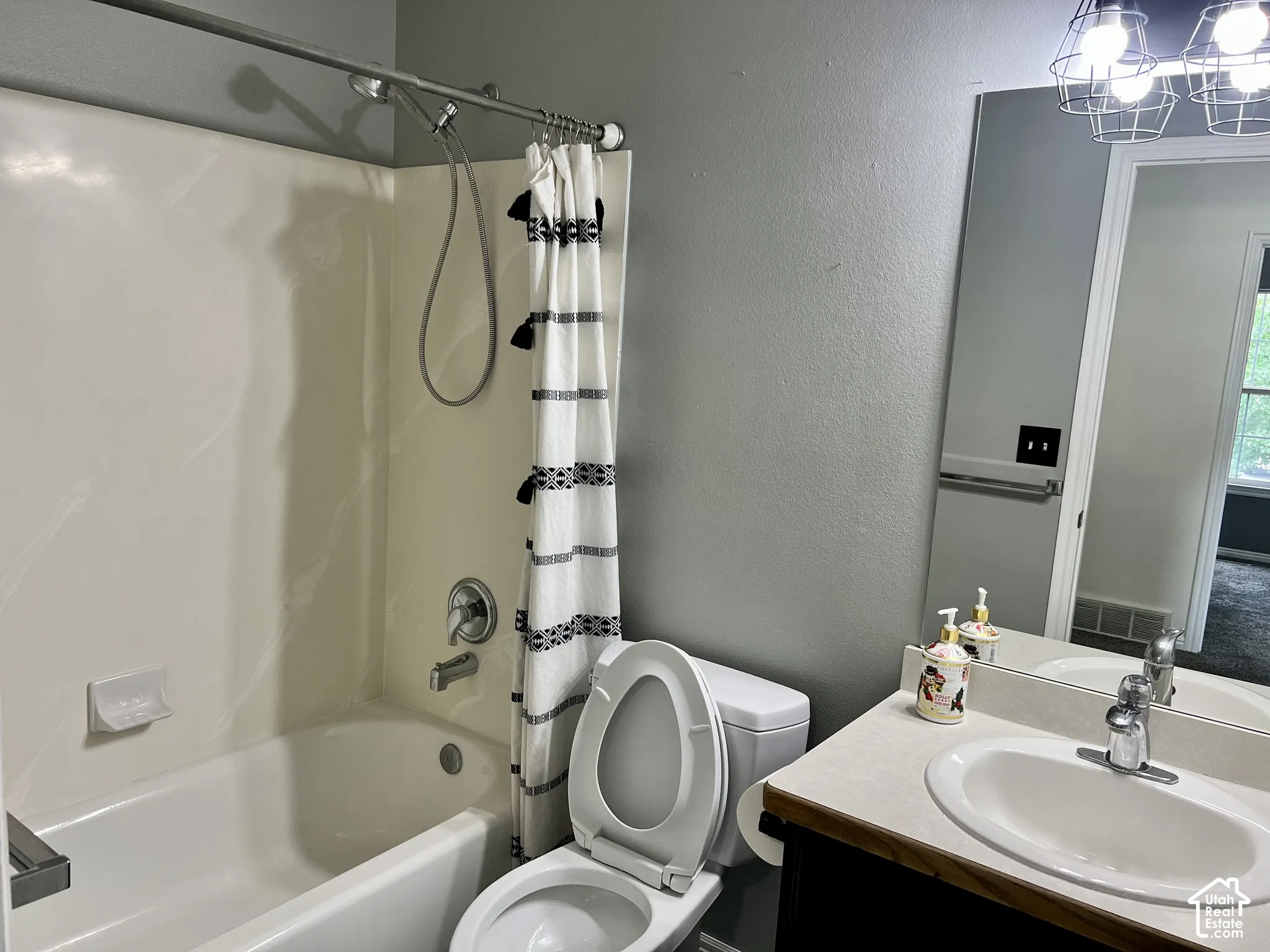 Bathroom featuring a composite shower and tub surround, integrated vanity with a neutral countertop, undermount sink, chrome faucet hardware, and industrial-style cage lighting
