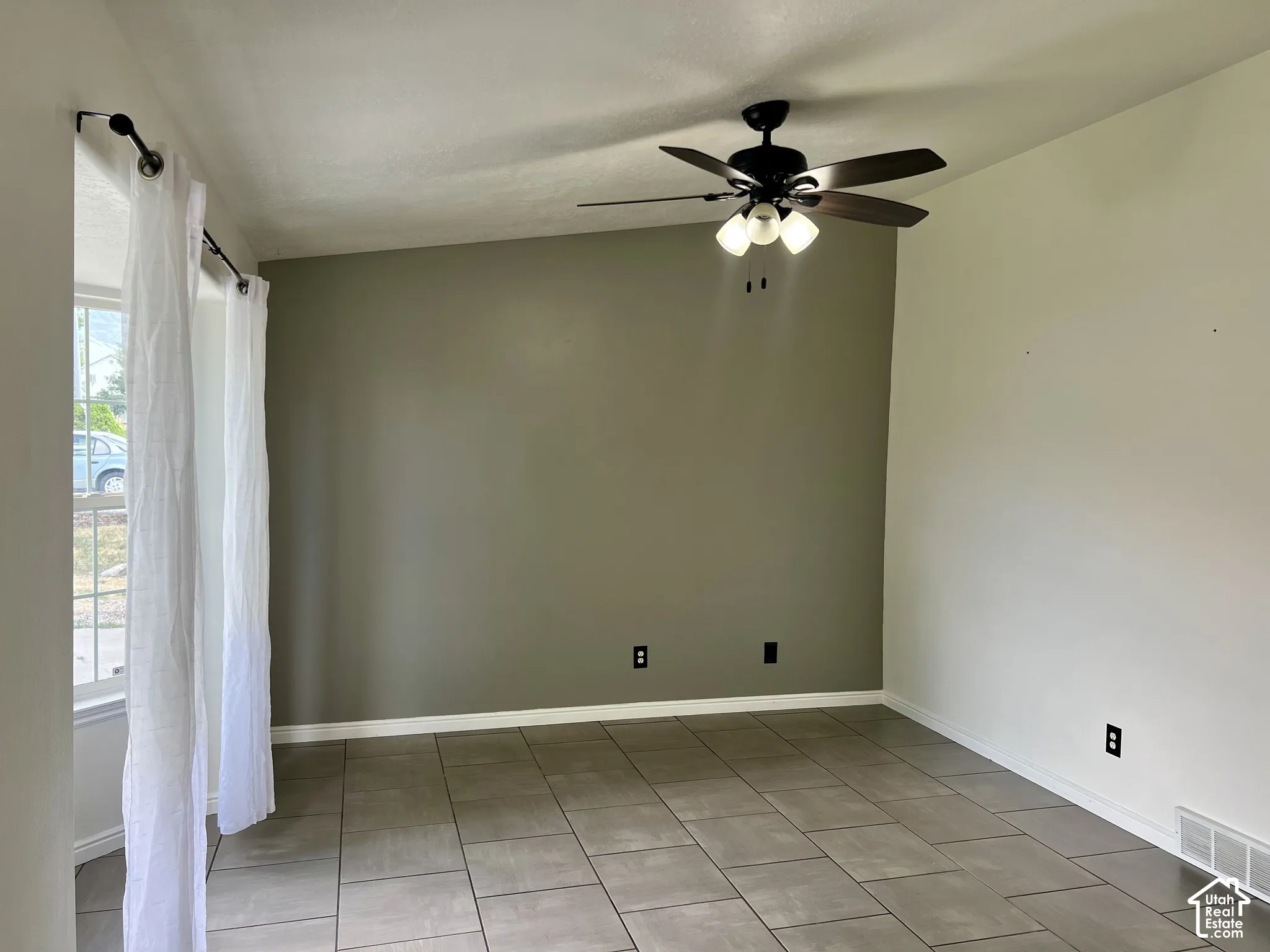 Room featuring large-format ceramic tile flooring, a vaulted ceiling, a multi-blade ceiling fan with integrated lighting, and a multi-pane window