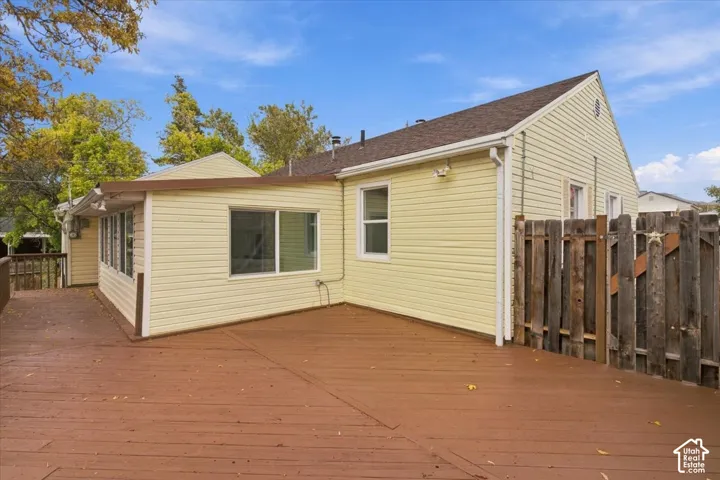 Exterior featuring light-colored horizontal siding, a stained wood deck, and a vertical wood privacy fence