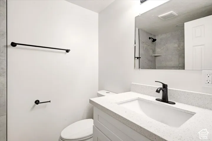 Bathroom featuring a white vanity with a light-toned solid surface countertop, an integrated sink, a matte black faucet, and matching matte black hardware