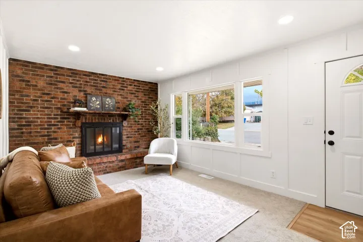 Exposed brick fireplace with a wood mantel, recessed ceiling lighting, and wall paneling