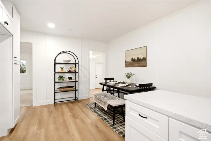 Custom white cabinetry featuring matte black hardware, stone-composite countertops, and wood-finish flooring