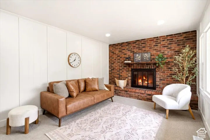 Exposed brick fireplace with a wood mantel and matching hearth, floor-to-ceiling vertical paneled wall, and recessed lighting