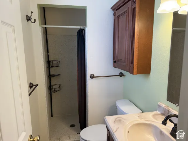 Built-in wood wall cabinet, stone-finish vanity countertop, under-mount sink with oil-rubbed bronze faucet, and walk-in shower