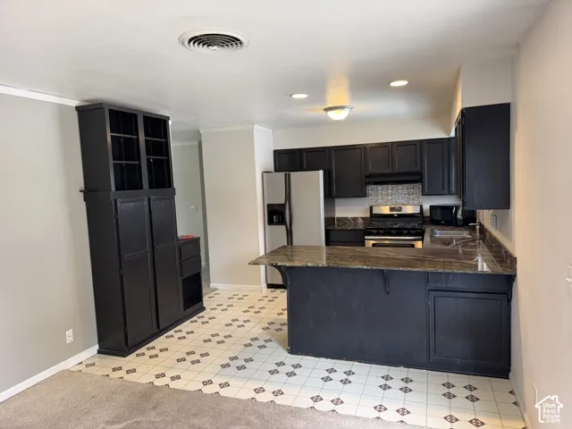 Kitchen featuring dark cabinetry, expansive stone-surface breakfast bar, tiled flooring with geometric accents, and built-in floor-to-ceiling storage cabinetry