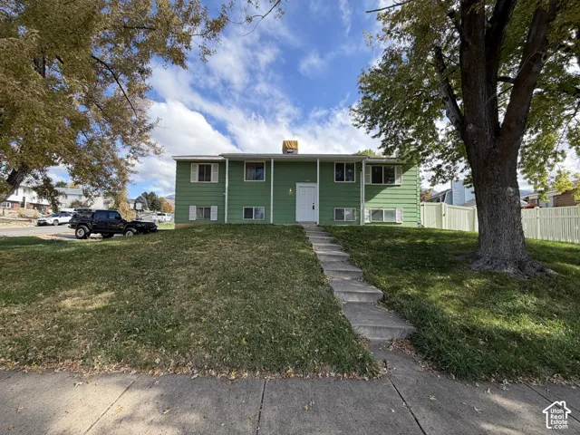 Split-level exterior featuring horizontal siding, a central white entry door, symmetrical window placement, and a concrete walkway