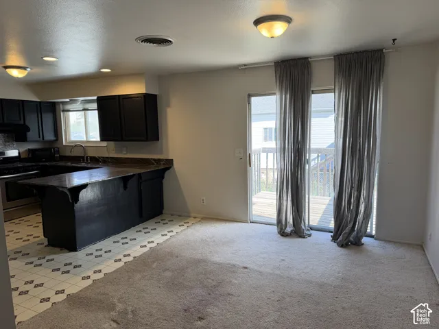 Kitchen featuring dark cabinetry, expansive countertop workspace, breakfast bar, and sliding glass doors providing external access