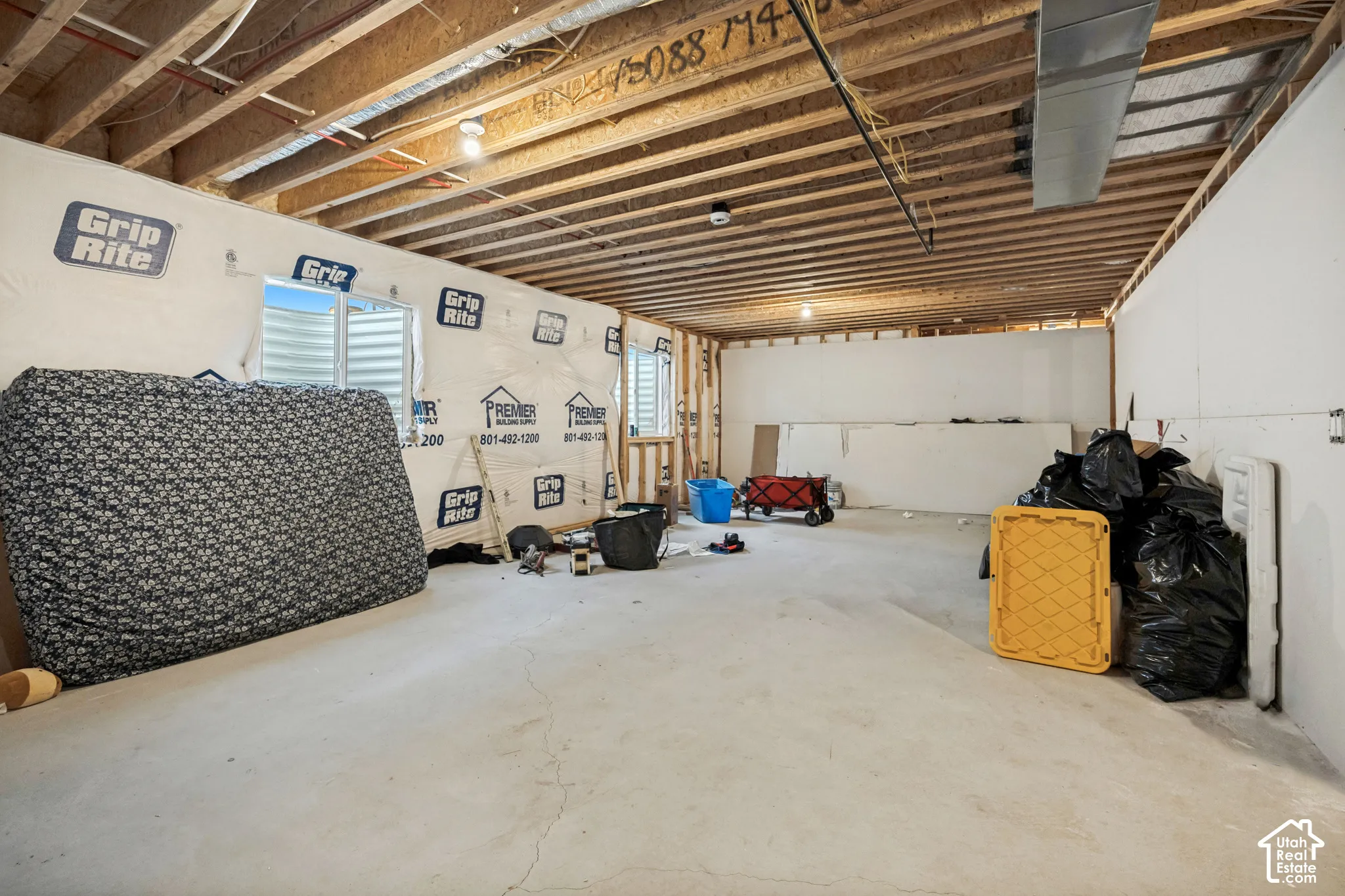 Unfinished lower-level space featuring an exposed joist ceiling, concrete flooring, and egress window wells