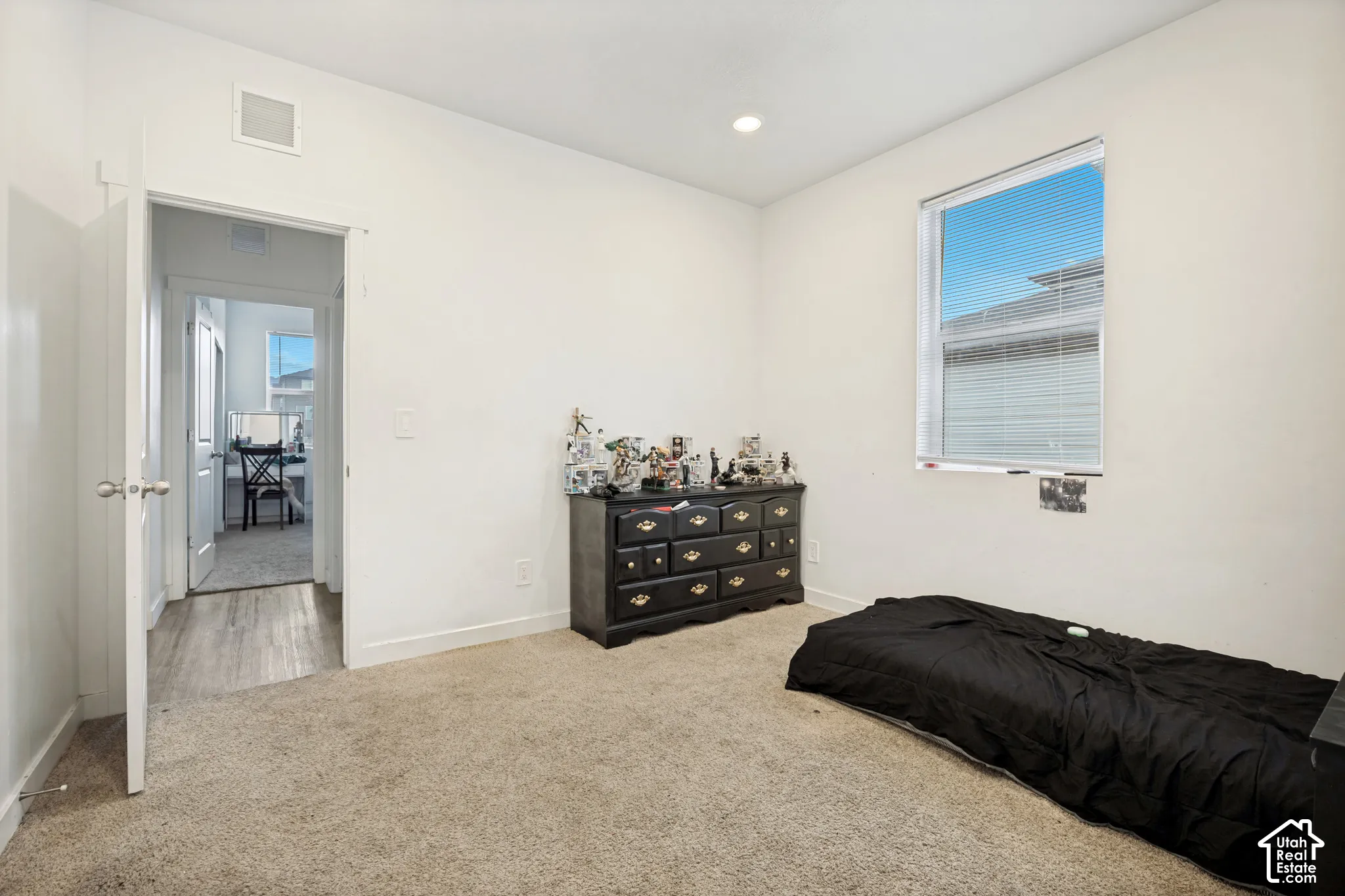 Neutral-toned carpeted flooring, recessed lighting, and a single-pane window