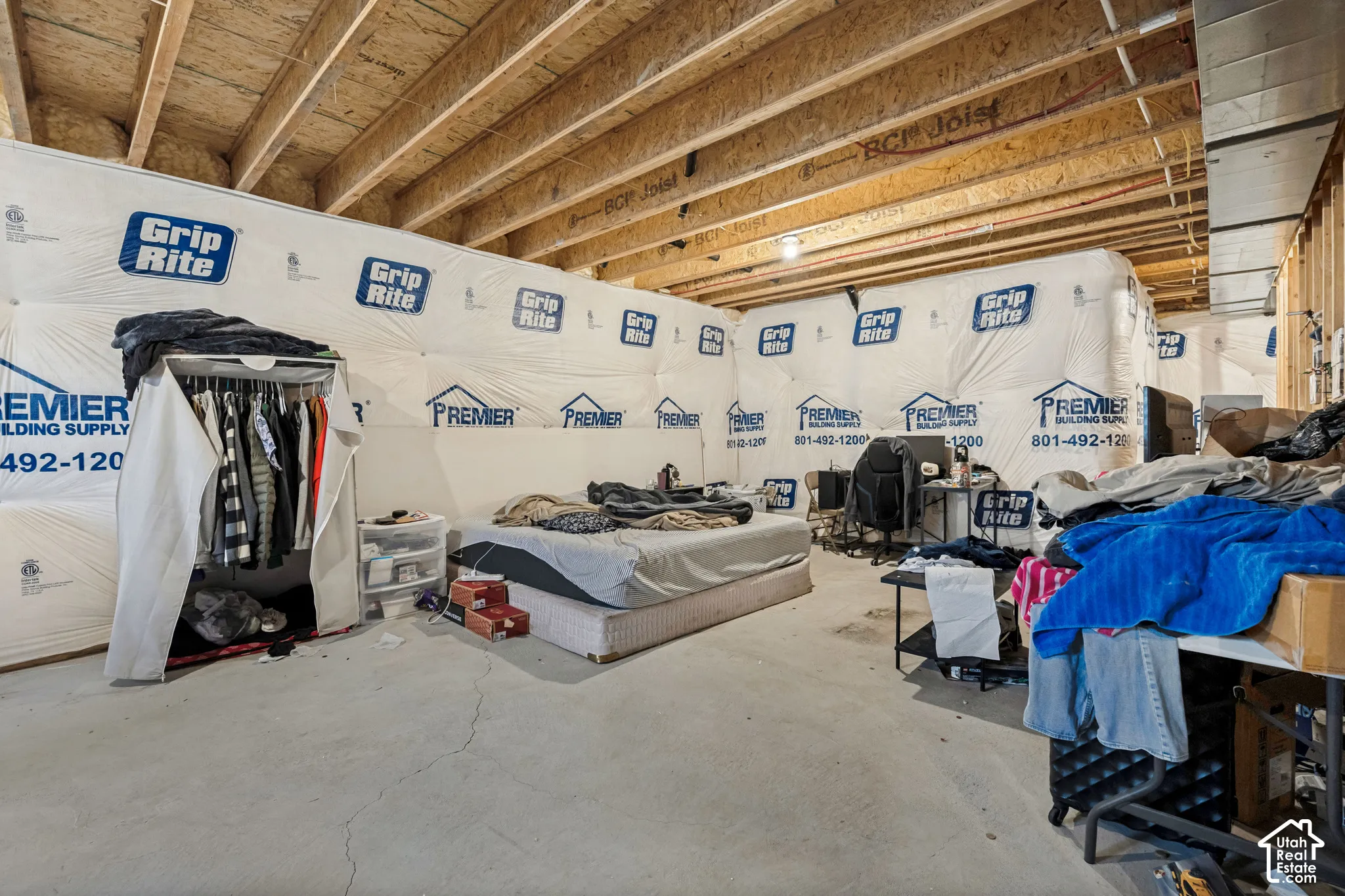 Unfinished basement space featuring exposed engineered wood joists, concrete flooring, and insulated foundation walls
