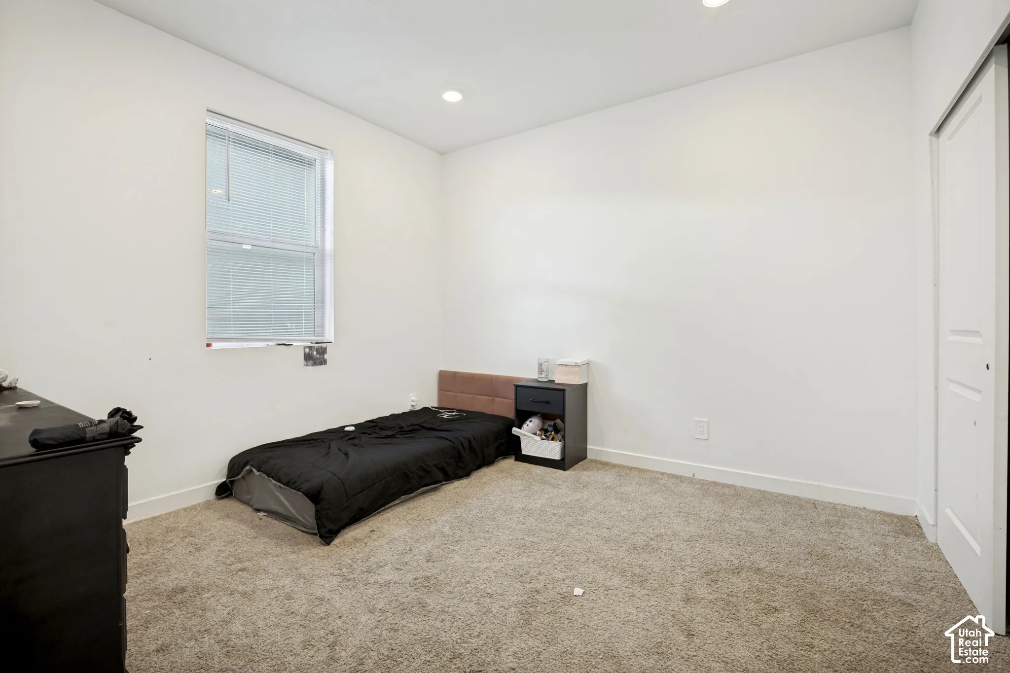 Neutral interior space featuring carpeted flooring, recessed ceiling lighting, a single-pane window, and a paneled closet door