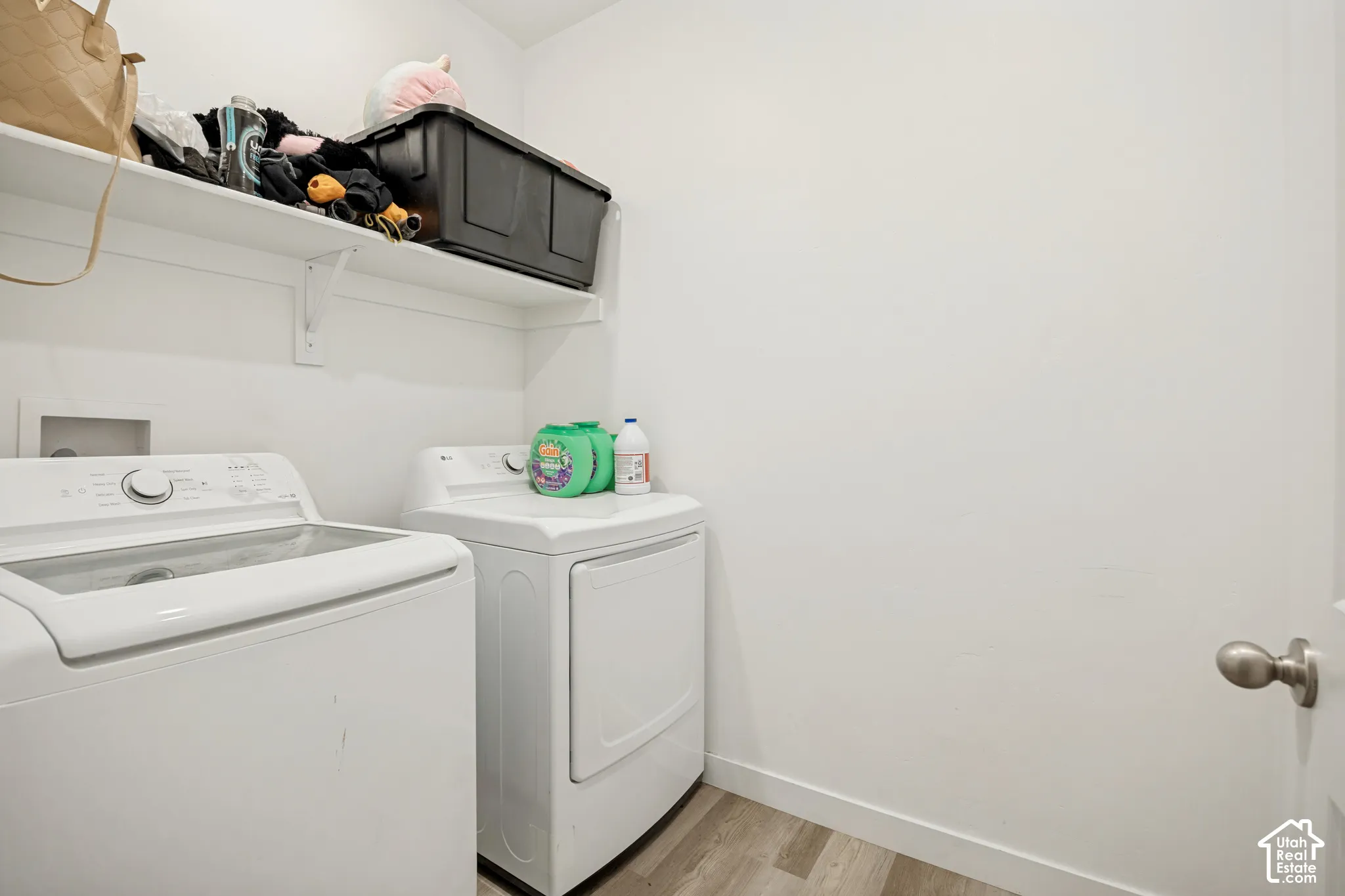 Dedicated laundry space featuring wood-finish flooring and a white built-in wall shelf