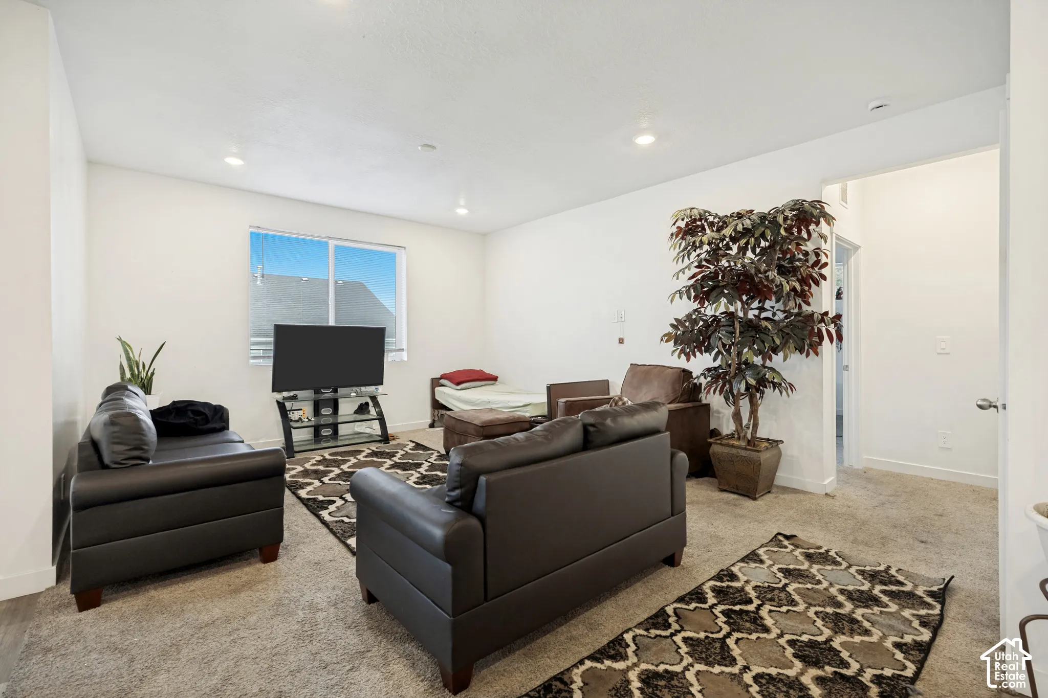 Neutral-toned carpeted flooring, recessed ceiling lighting, and a large window