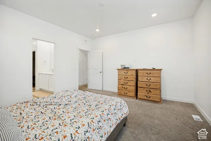 Neutral-toned interior space featuring recessed ceiling lighting, wall-to-wall carpeting, and a multi-panel interior door