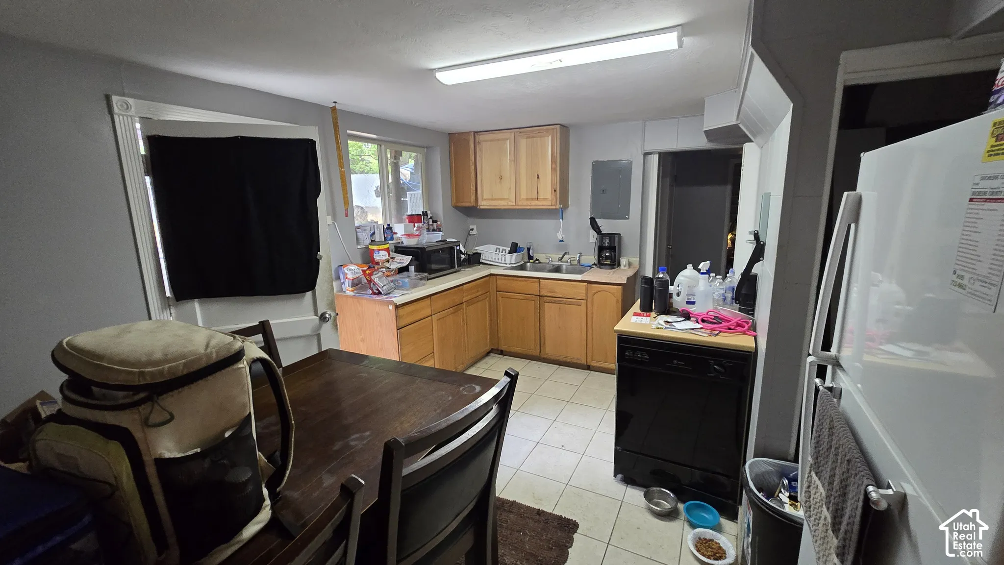 Kitchen featuring wooden cabinetry, solid surface countertops, a stainless steel dual-basin sink, and tiled flooring