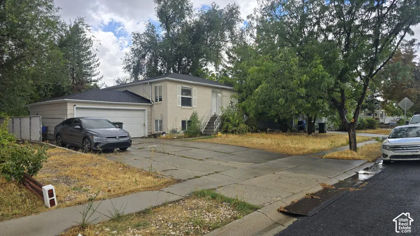 Exterior featuring masonry siding, attached two-car garage, concrete driveway, and mature landscaping