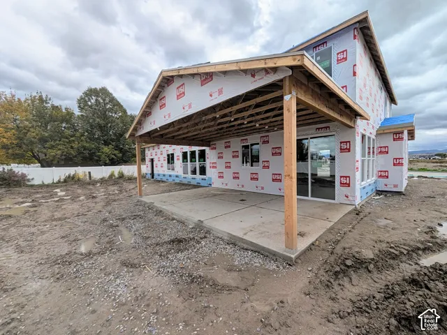 Covered concrete patio featuring timber framing, sliding glass doors, and white vinyl perimeter fencing