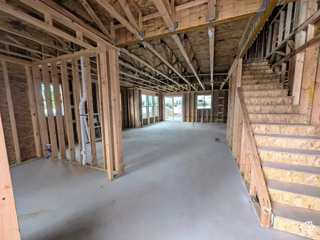 Structural wood framing featuring exposed trusses, engineered wood stair system, concrete slab foundation, and installed windows