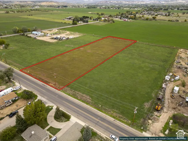 Expansive parcel of open land featuring direct paved road access, utility poles on-site, and a mountain backdrop