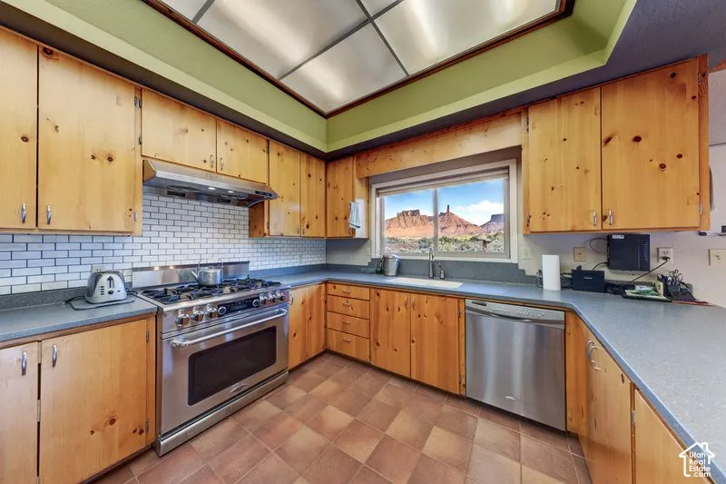 Kitchen featuring knotty wood cabinetry, stainless steel gas range, subway tile backsplash, recessed ceiling lighting, and mountain scenery