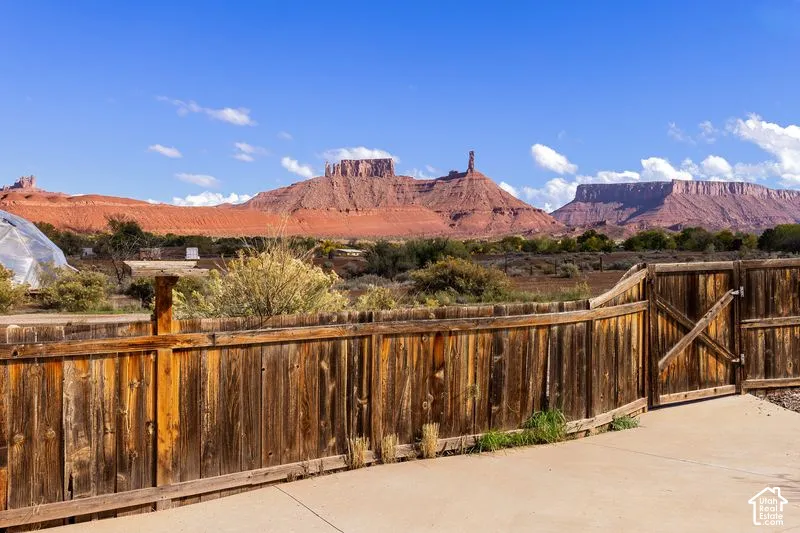 Exterior concrete patio enclosed by a wood privacy fence, featuring desert landscape and prominent red rock mountain formations