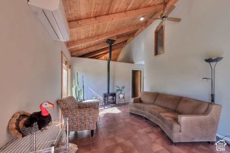 Vaulted wood-plank ceiling featuring exposed beams, ceramic tile flooring, and a black cast-iron wood-burning stove