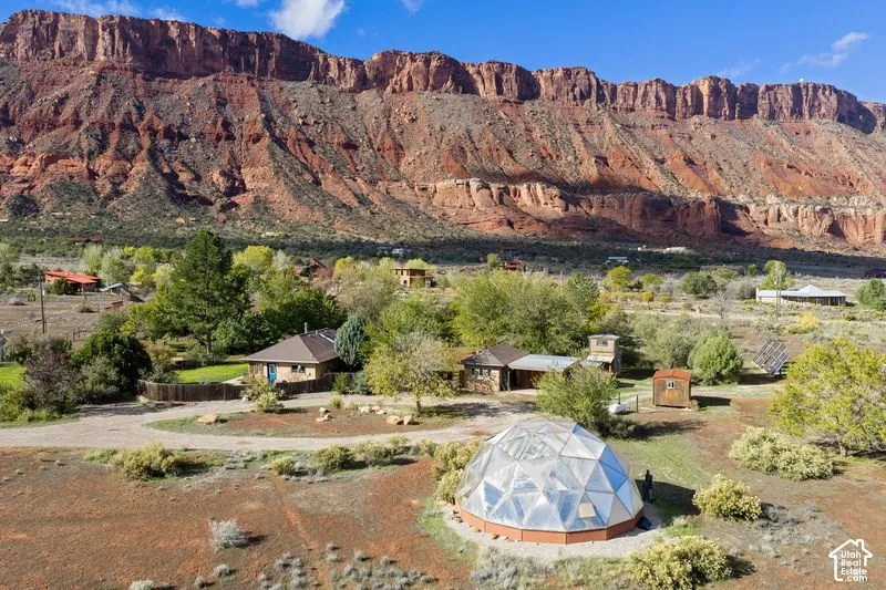 Expansive lot featuring a geodesic dome structure, mature vegetation, and a prominent red rock mountain backdrop