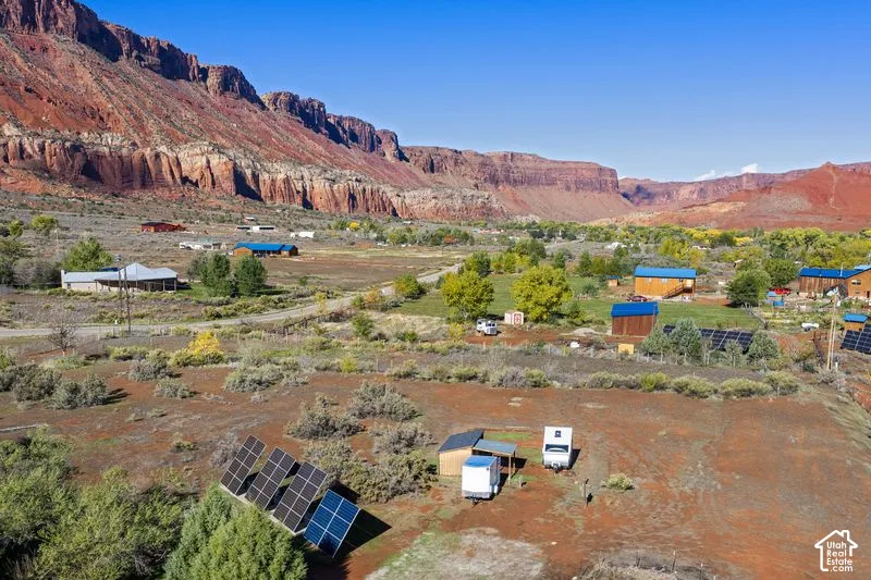 Expansive desert landscape featuring red rock mountain formations, native vegetation, and ground-mounted solar panel arrays