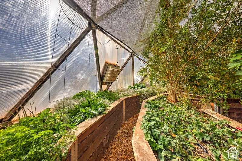Geodesic-style greenhouse featuring a structural metal frame, translucent polycarbonate panels, a mechanical ventilation system, and tiered raised garden beds constructed from wood