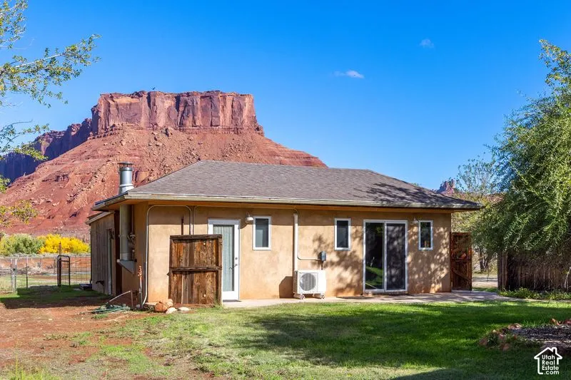Detached Studio Stucco exterior featuring a metal chimney, sliding glass door, and a concrete patio area set against a mountain backdrop